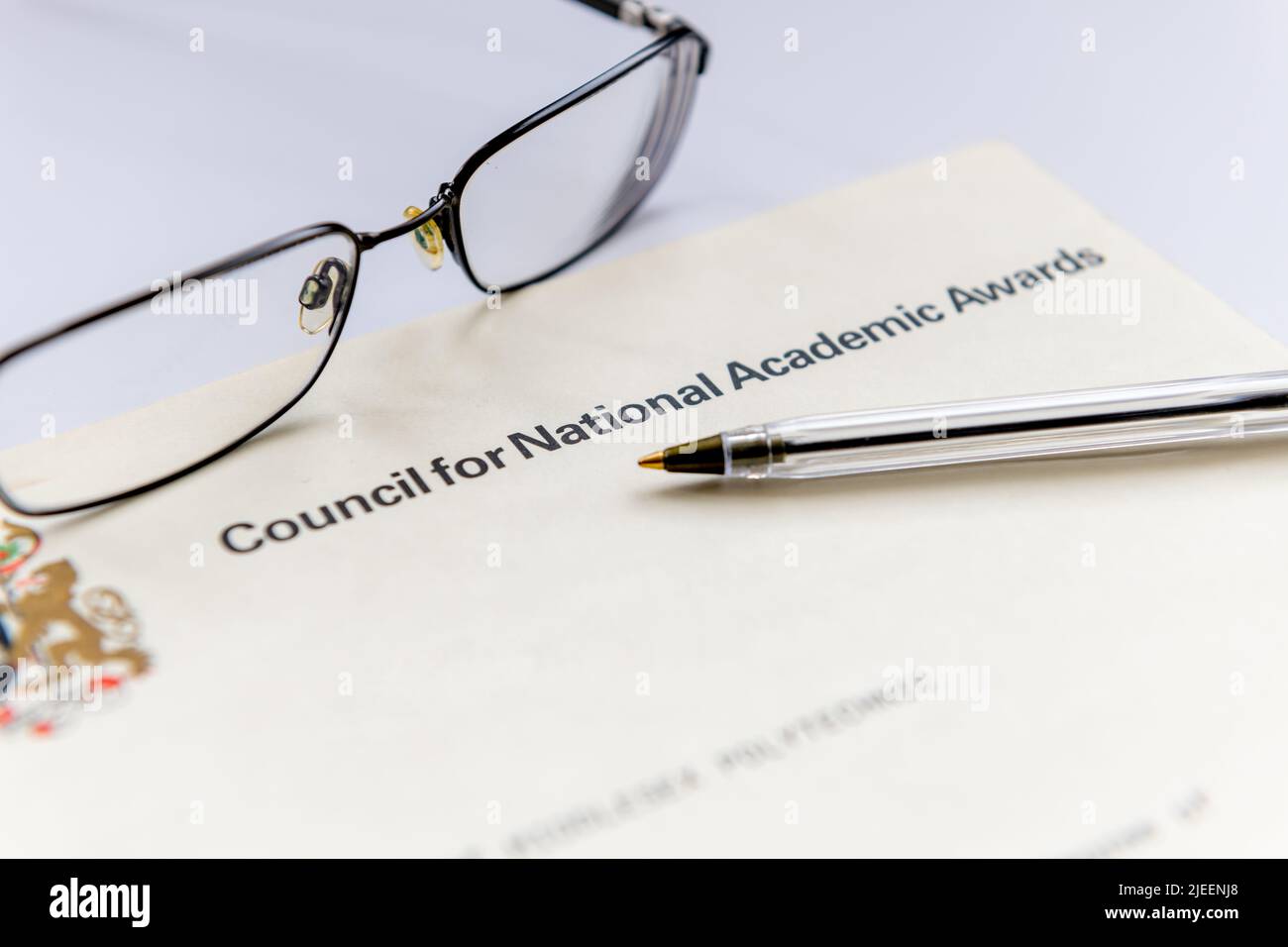 A United Kingdom higher education certificate issued by the Council for National Academic Awards shown with a pair of glasses and a pen. Stock Photo