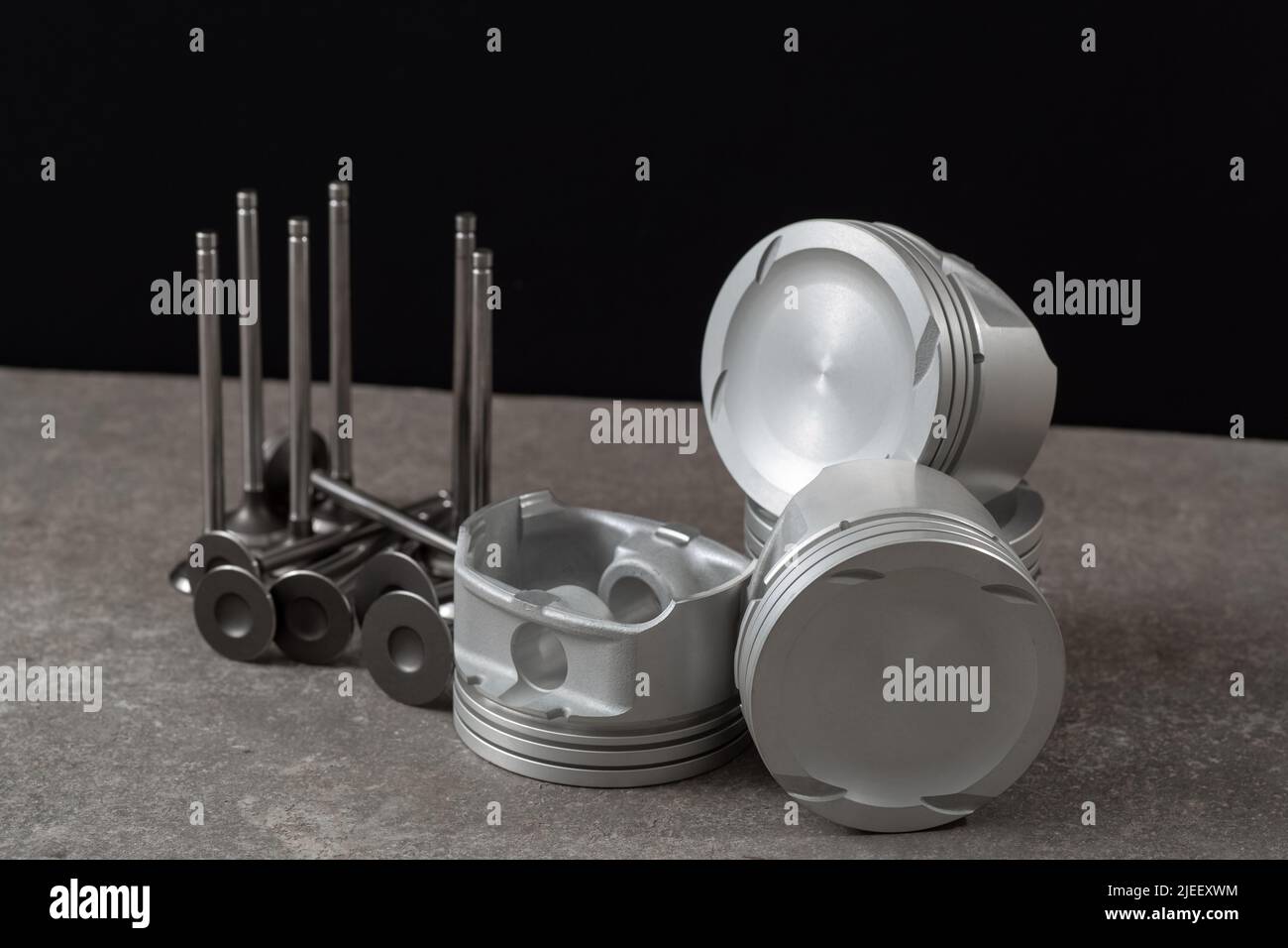 Set of new car pistons and valves on concrete gray background, car