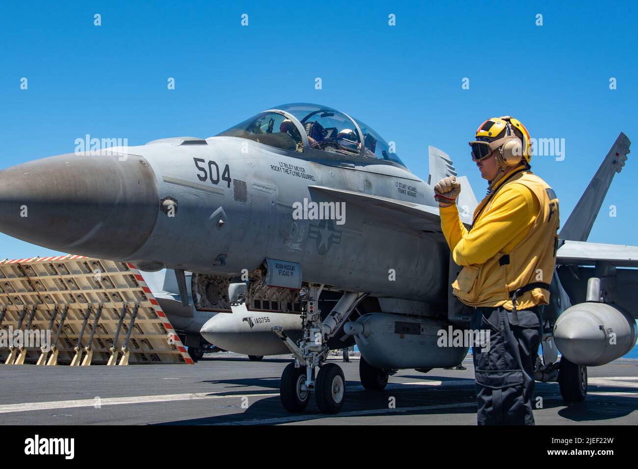 220620-N-BR419-1015 PHILIPPINE SEA (June 20, 2022) Aviation Boatswain’s Mate (Handling) 1st Class Dominic Caviness, from Aurora, Colorado, directs an EA-18G Growler attached to the Shadowhawks of Electronic Attack Squadron (VAQ) 141, on the flight deck of the U.S. Navy’s only forward-deployed aircraft carrier USS Ronald Reagan (CVN 76). The primary role of EA-18G Growlers is to disrupt the ability to communicate between units in combat through the use of electronic warfare. Ronald Reagan, the flagship of Carrier Strike Group 5, provides a combat-ready force that protects and defends the United Stock Photo