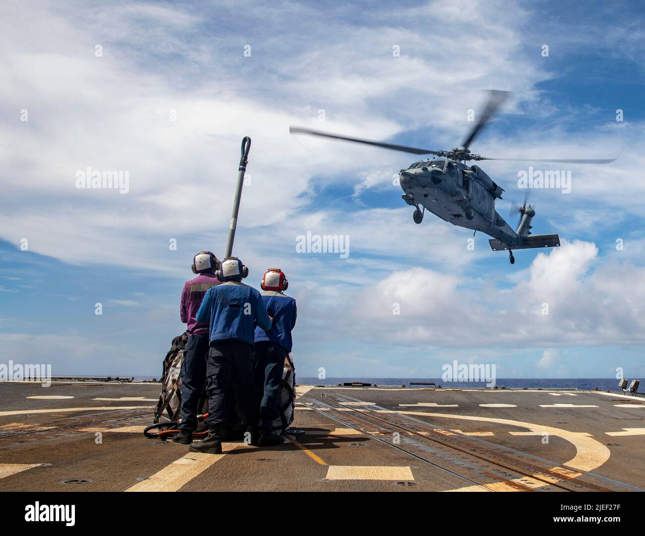 PHILIPPINE SEA (June 2, 2022) Sailors aboard the Arleigh Burke-class guided-missile destroyer USS Dewey (DDG 105) prepare to attach cargo to an MH-60S Sea Hawk helicopter, assigned to the “Chargers” of Helicopter Sea Combat Squadron (HSC) 14, during a vertical replenishment with the Ticonderoga-class guided-missile cruiser USS Mobile Bay (CG 53). Abraham Lincoln Strike Group is on a scheduled deployment in the U.S. 7th Fleet area of operations to enhance interoperability through alliances and partnerships while serving as a ready-response force in support of a free and open Indo-Pacific region Stock Photo