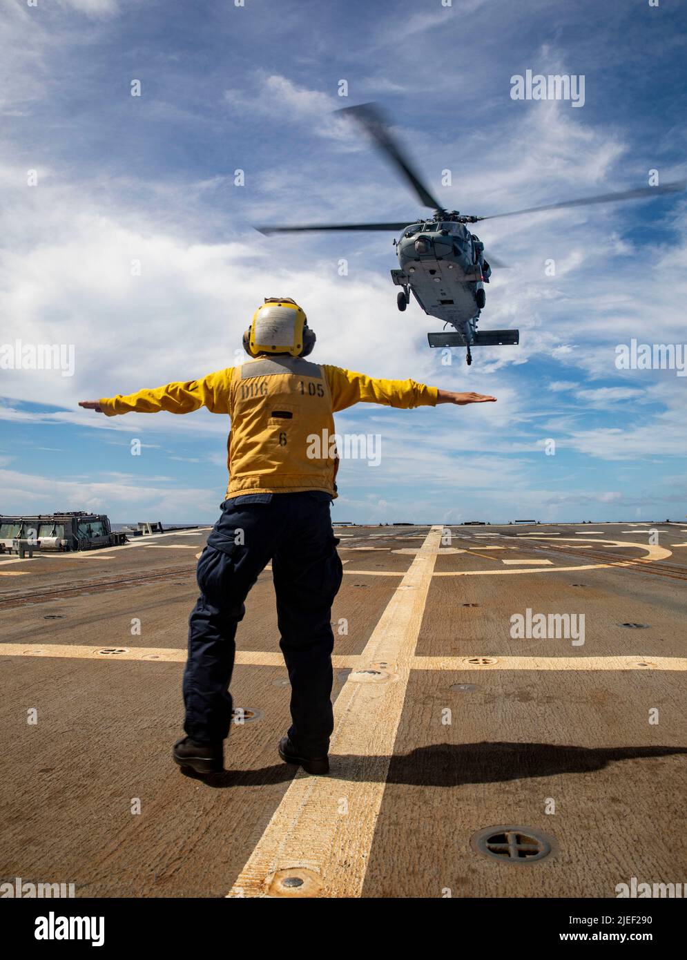 PHILIPPINE SEA (June 2, 2022) Boatswain’s Mate 3rd Class Ashley Iuli, from Los Angeles, signals to the pilot of an MH-60S Sea Hawk helicopter, assigned to the “Chargers” of Helicopter Sea Combat Squadron (HSC) 14, as it takes off from the flight deck of The Arleigh Burke-class guided-missile destroyer USS Dewey (DDG 105) during a vertical replenishment with Ticonderoga-class guided-missile cruiser USS Mobile Bay (CG 53). Abraham Lincoln Strike Group is on a scheduled deployment in the U.S. 7th Fleet area of operations to enhance interoperability through alliances and partnerships while serving Stock Photo
