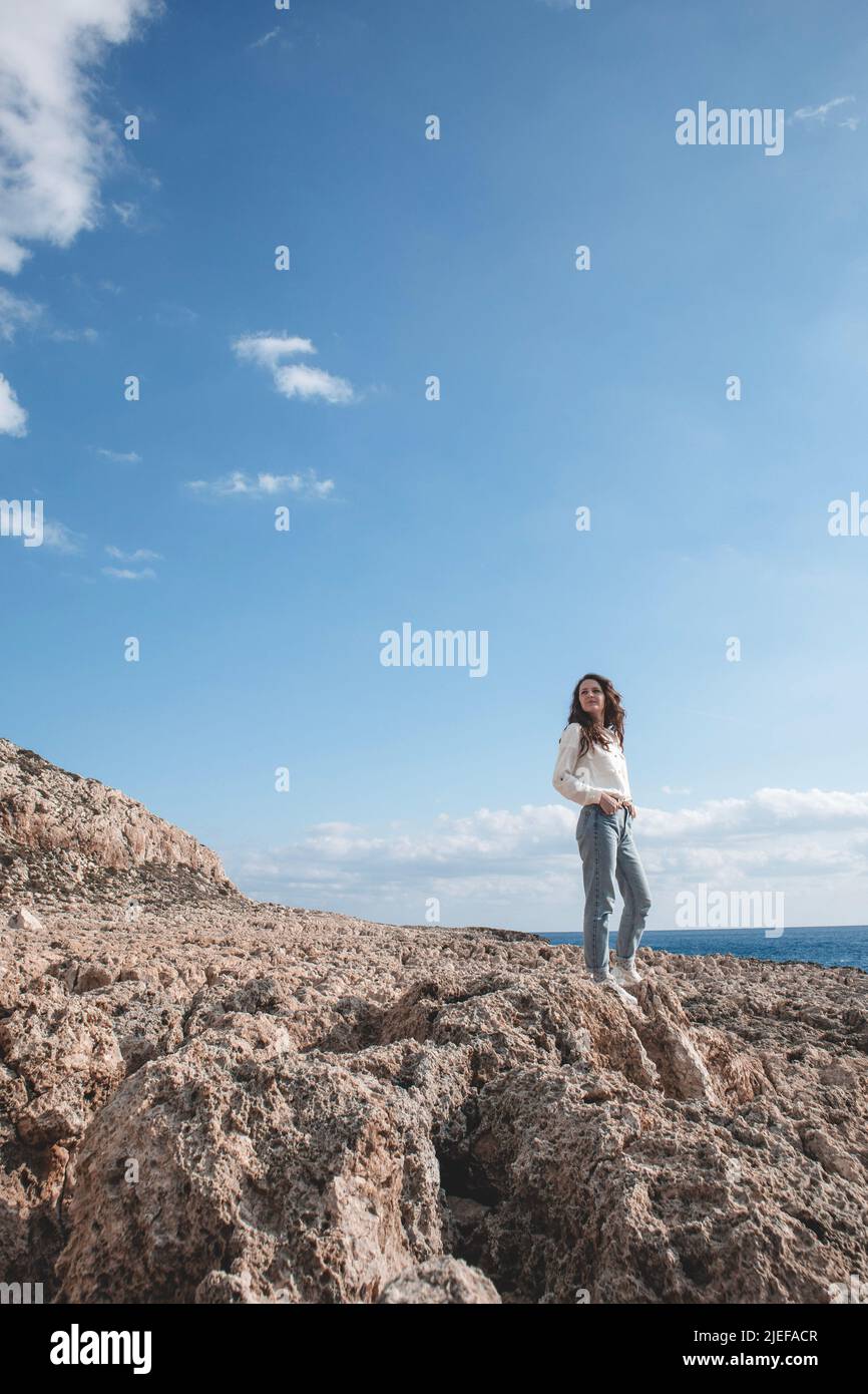 Young woman is standing in a desert ground in front of the mountain Cape Greco Stock Photo