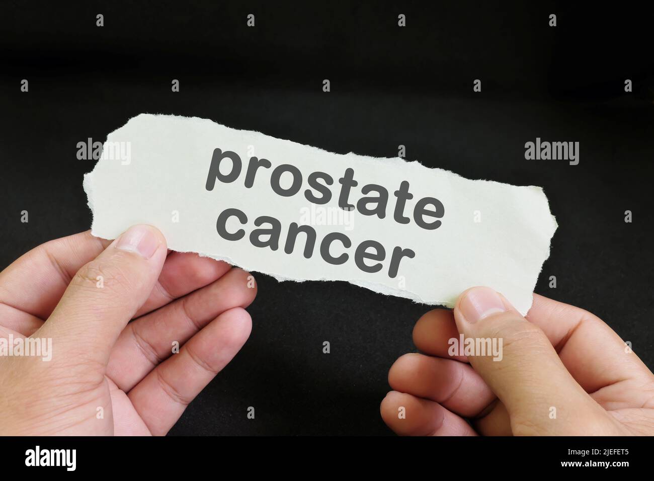 Prostate Cancer diagnosis concept. Hand holding paper with written word text in dark black background. Stock Photo