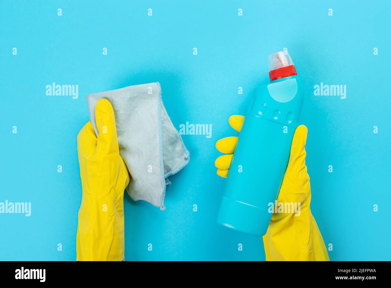 The hands of a housewife in yellow rubber protective gloves hold a