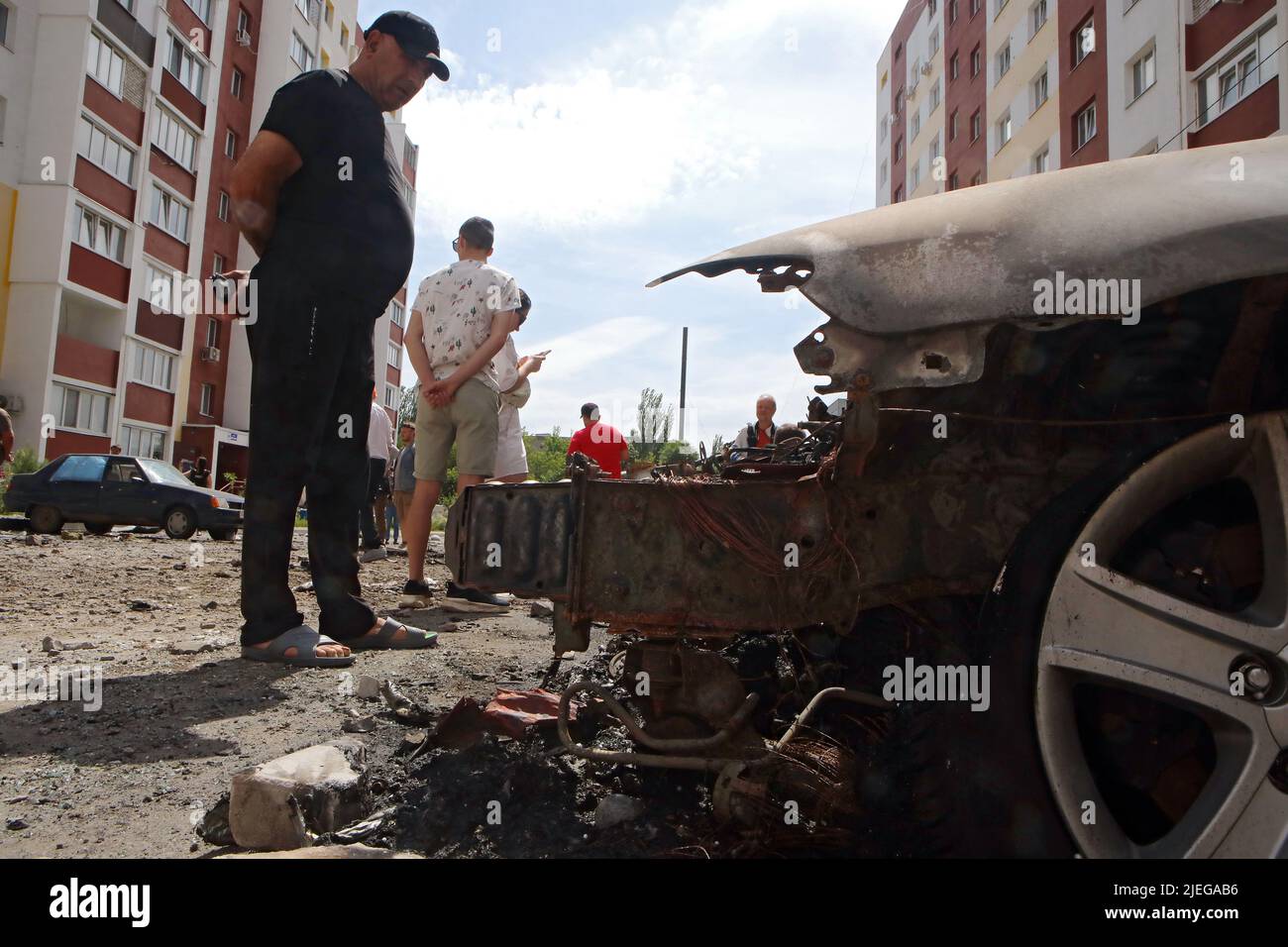 KHARKIV, UKRAINE - JUNE 26, 2022 - Onlookers observe damage caused by the shelling of a northern neighbourhood by Russian troops with a BM-30 Smerch m Stock Photo