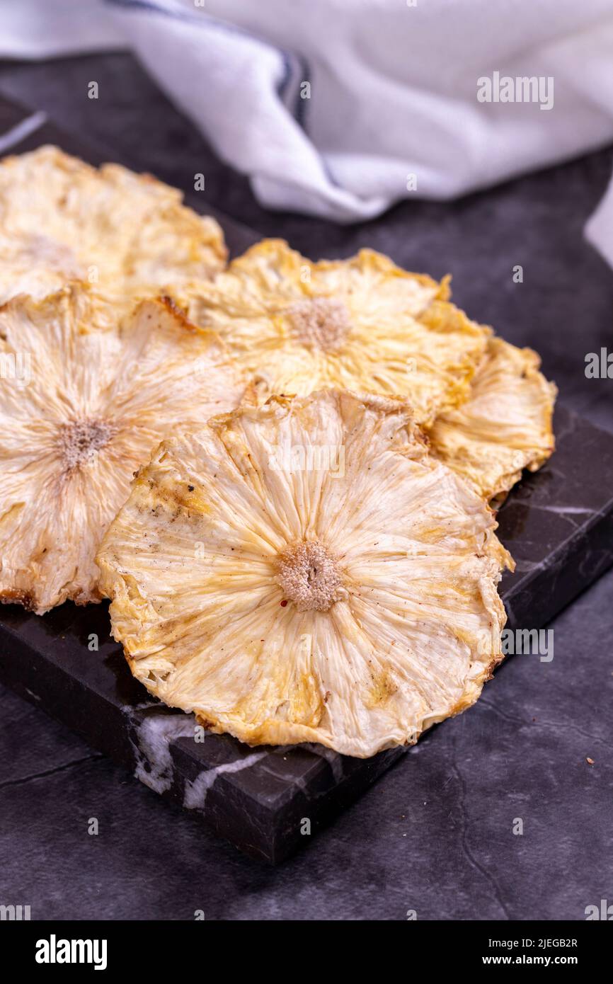Dried pineapple slices. Sliced dried pineapple on dark background. Sun-dried fruit. close up Stock Photo