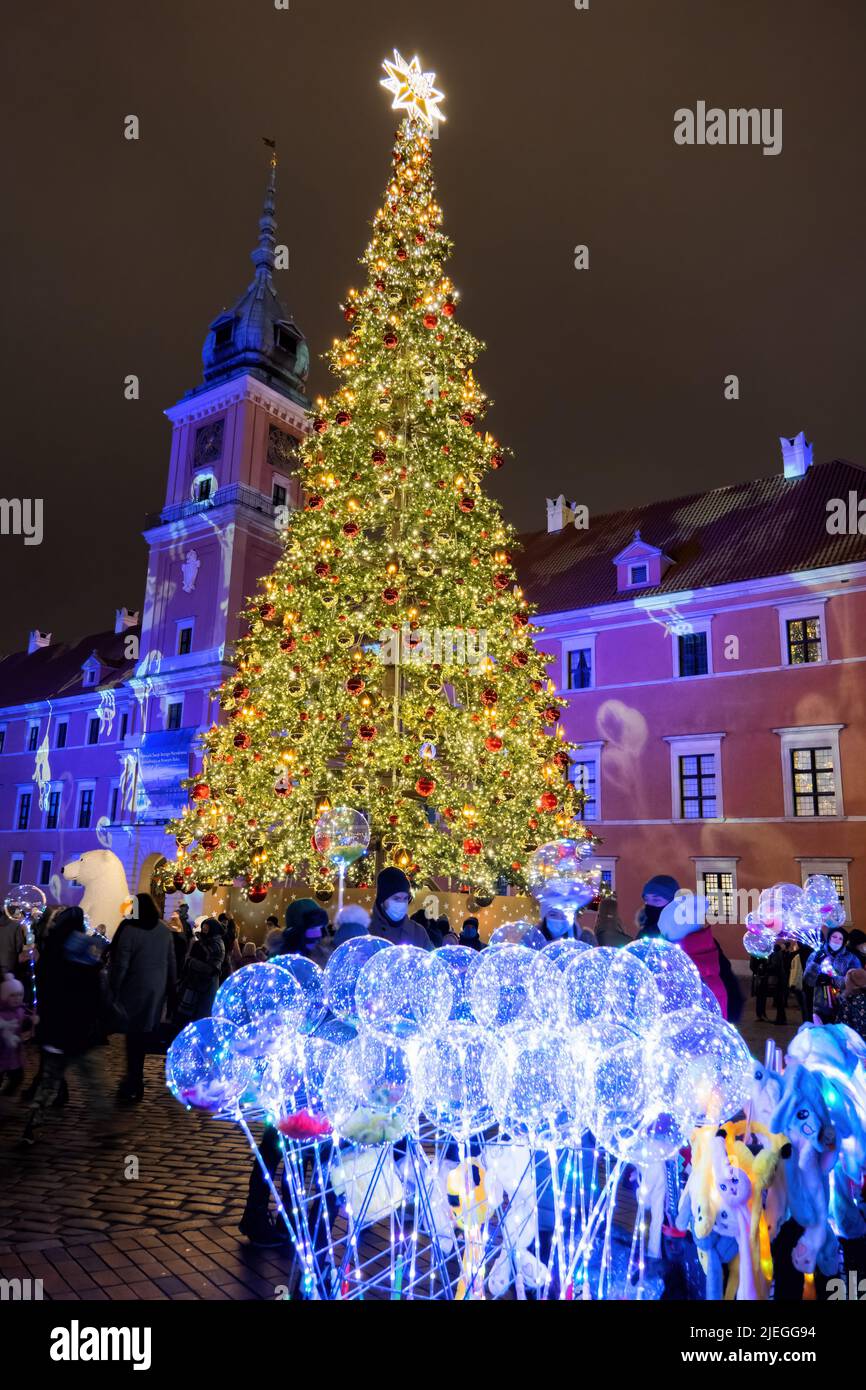 Warsaw, Poland - December 12, 2020: People at Christmas tree and led balloons for sale on the Castle Square at night in the Old Town, winter holiday t Stock Photo