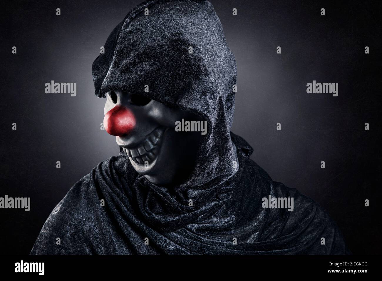 Scary clown showing his teeth over dark misty background Stock Photo