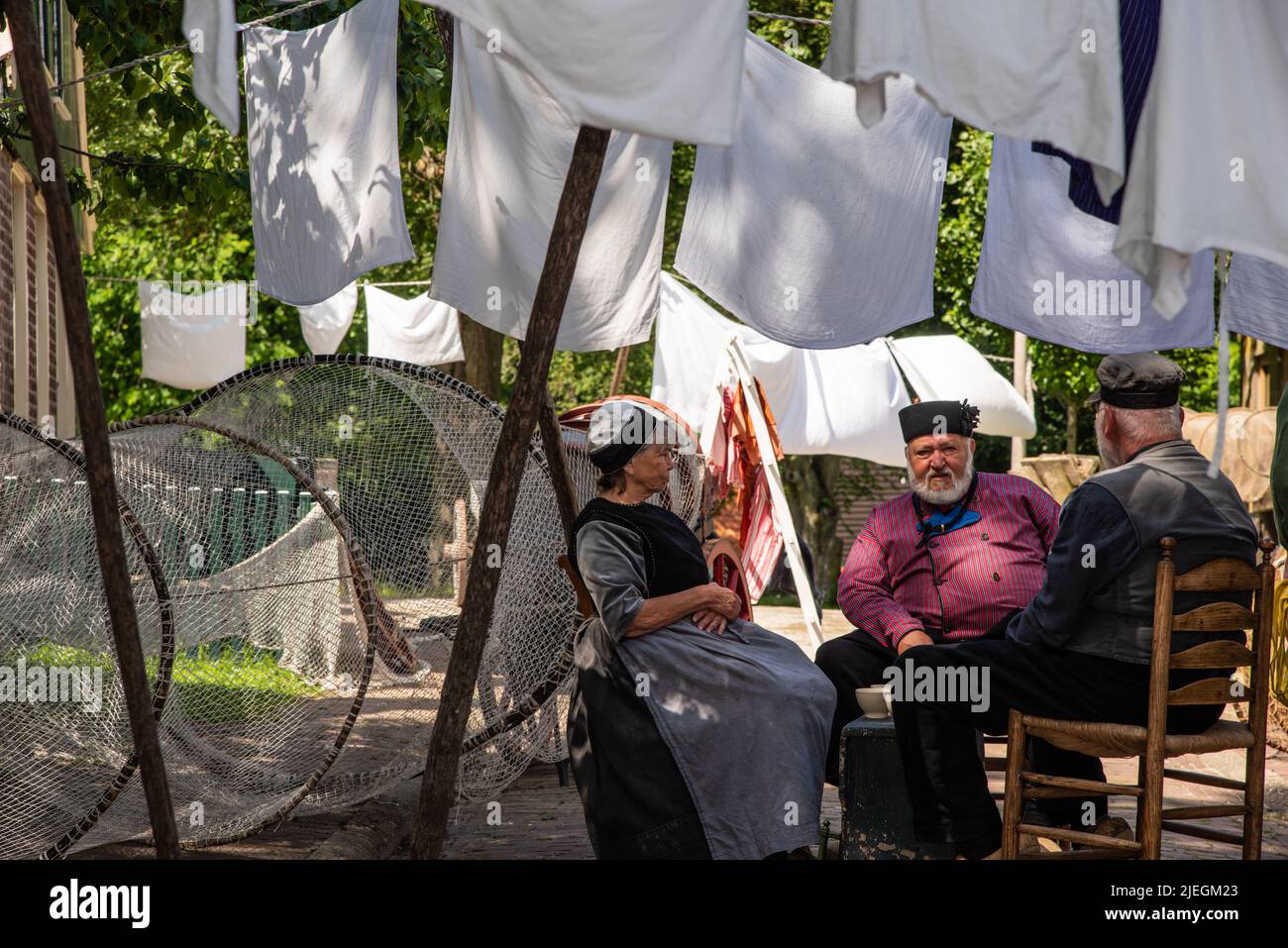 Enkhuizen, Netherlands. June 2022. Talking fishermen men and women and the backdrop of drying laundry. High quality photo. Selective focus. Stock Photo