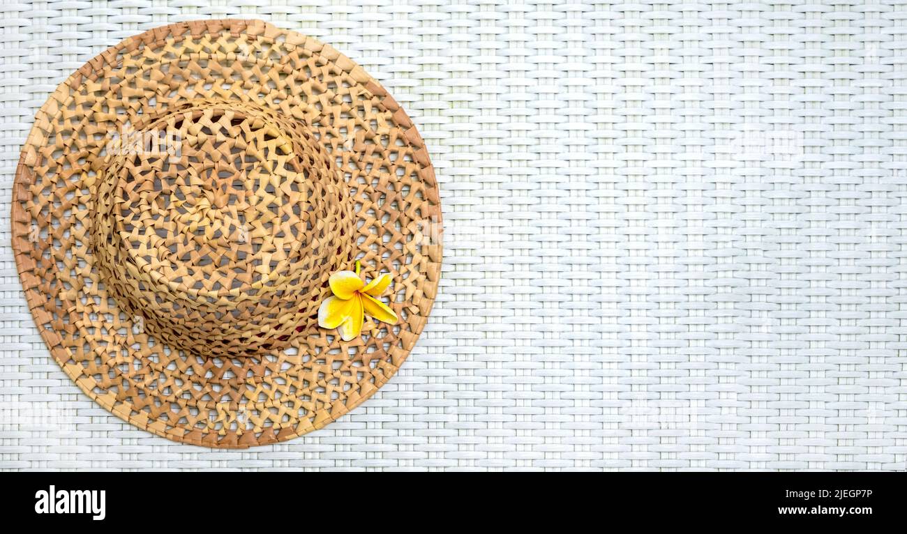 Travel.. Summer mockup. Straw hat on a white textured background with a frangipani flower. View from above. The concept of holidays, vacations and Stock Photo