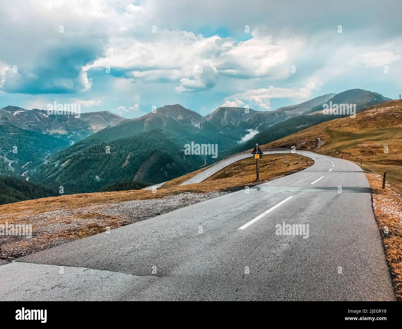 Mountain serpentine in the Alps. An empty road against the backdrop of mountains and cloudy skies. Europe Stock Photo