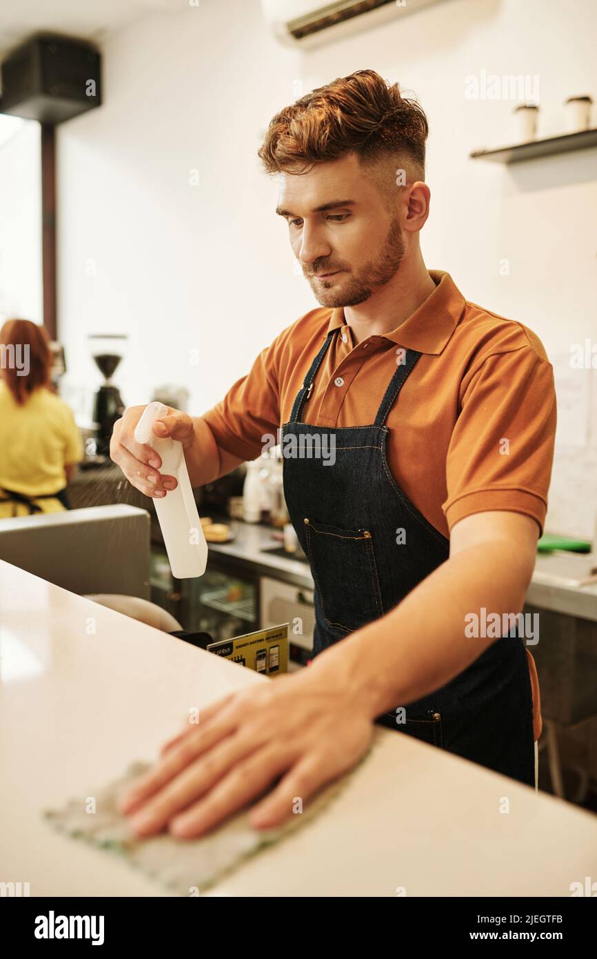 barista cleaning counter with disinfecting detergent to keep