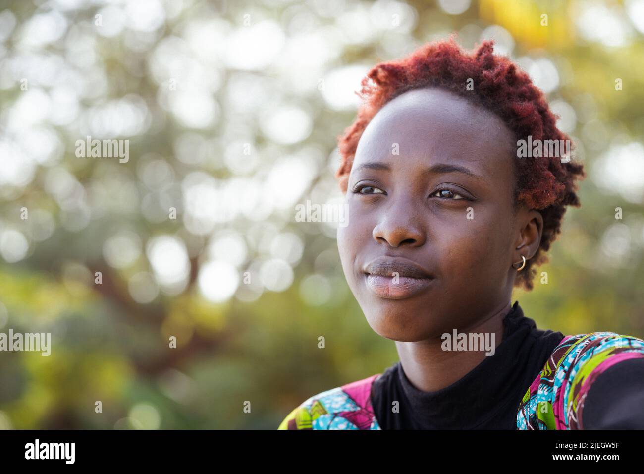 Front view of a melancholy young African teenager in love, dreaming about her favorite movie star Stock Photo