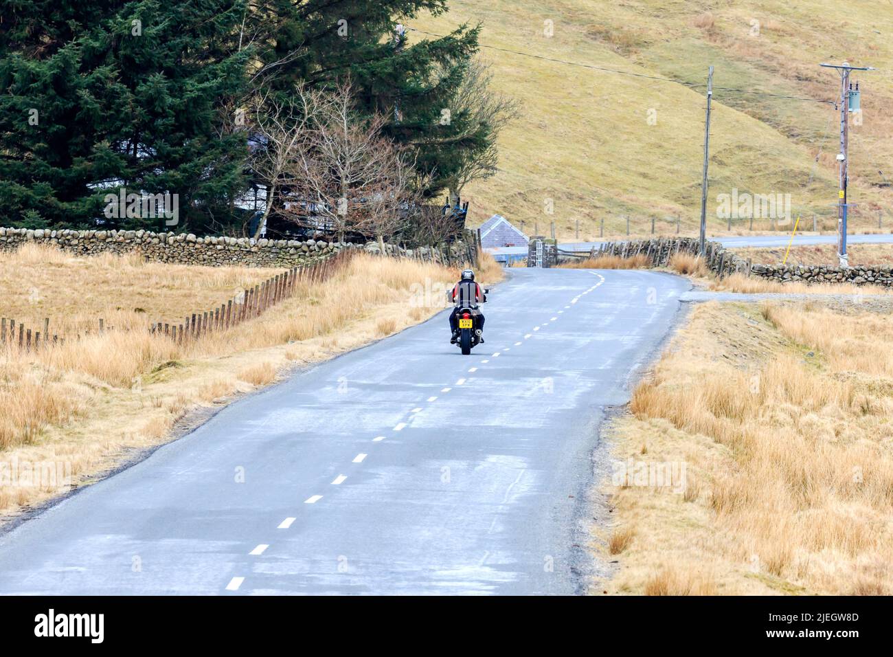 Birkhill, Scotland - March 26, 2022: Rear view of a motorcyclist riding on a county road towards the town of Selkirk in the Scottish Borders Stock Photo