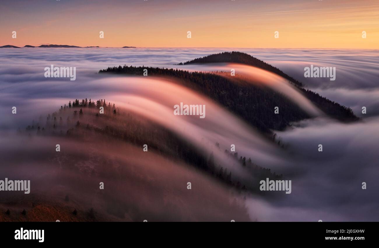Beautiful landscape, misty fog on mountain slopes, abstract view over clouds. Stock Photo