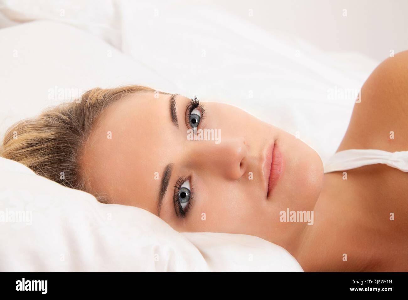 Eine junge Frau liegt wach im Bett. Schlaflos und nachdenklich. Stock Photo