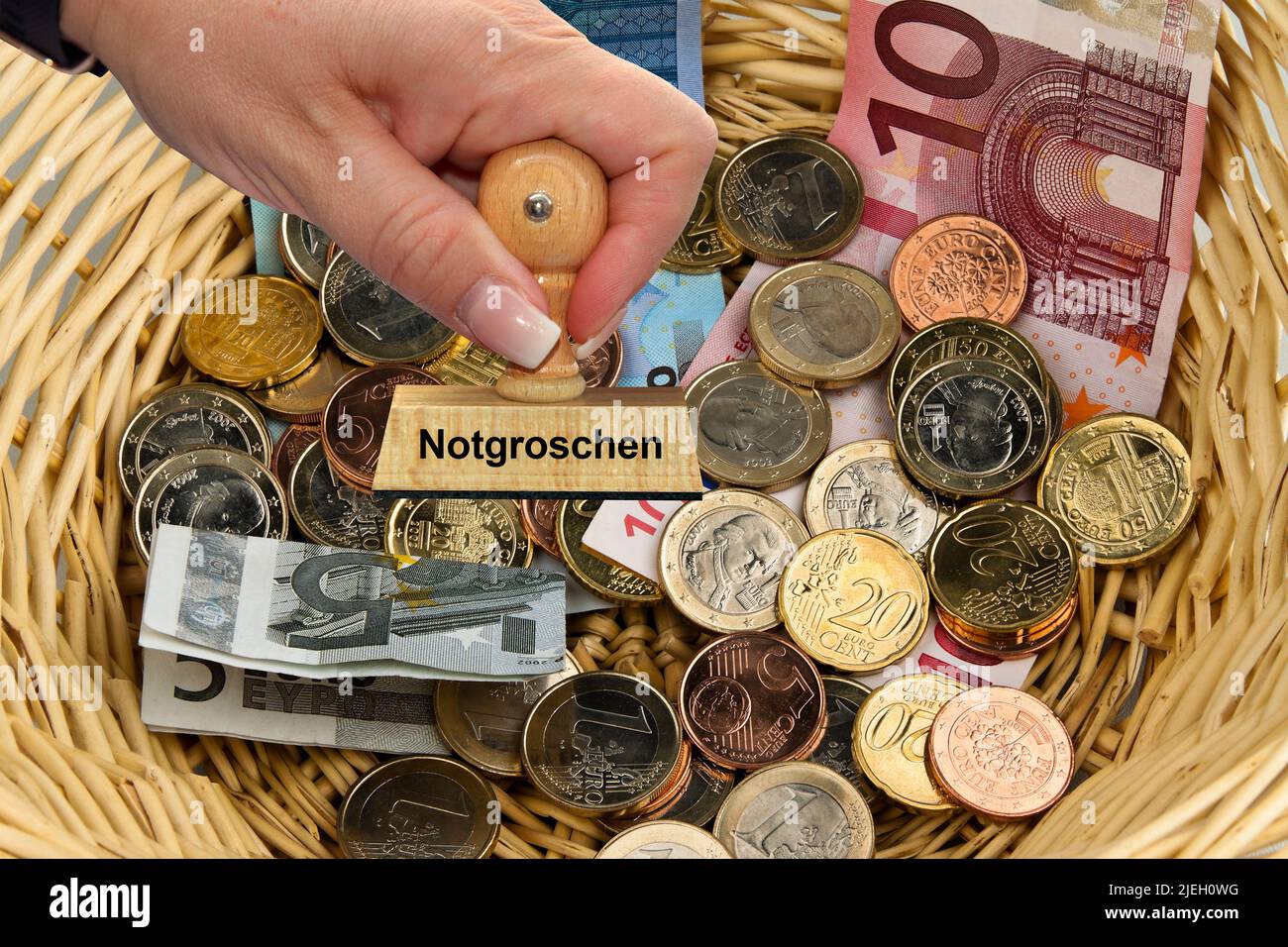 Viele verschiedene Euro-Banknoten und Münzen in einem. Korb, Stempel, Frauenhand, Notgroschen, Mindesteinkommen, Stock Photo