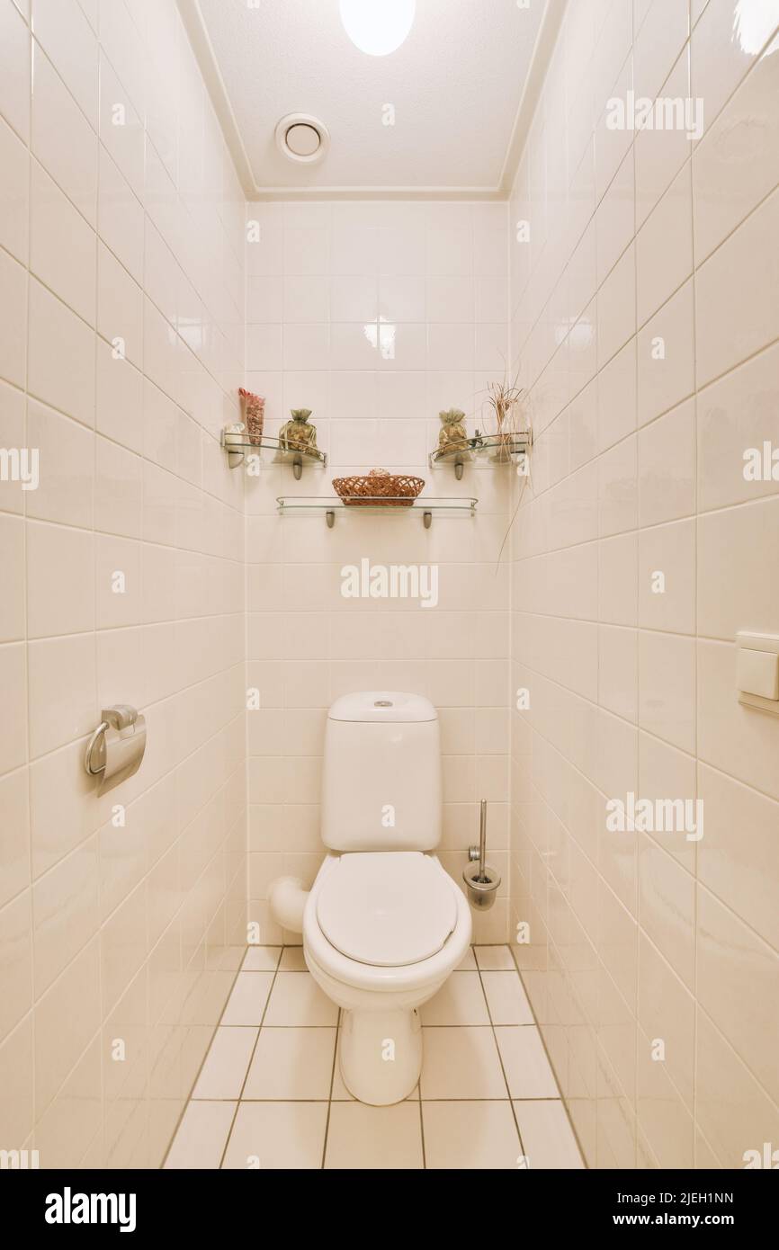 Wall hung toilet and small sink in corner in lavatory room with beige