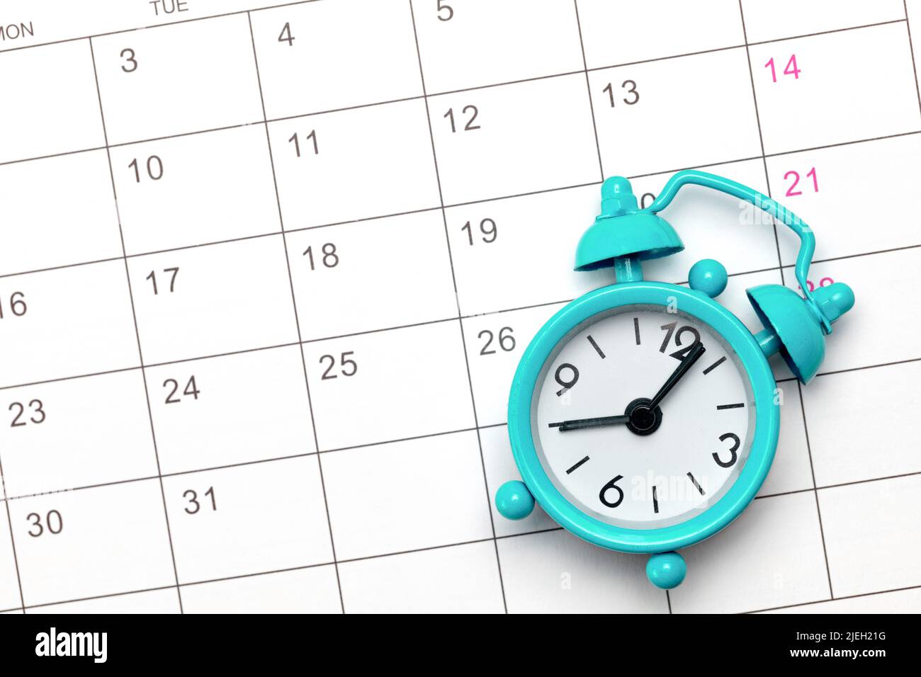 Green alarm clock on the background of an empty calendar. Stock Photo