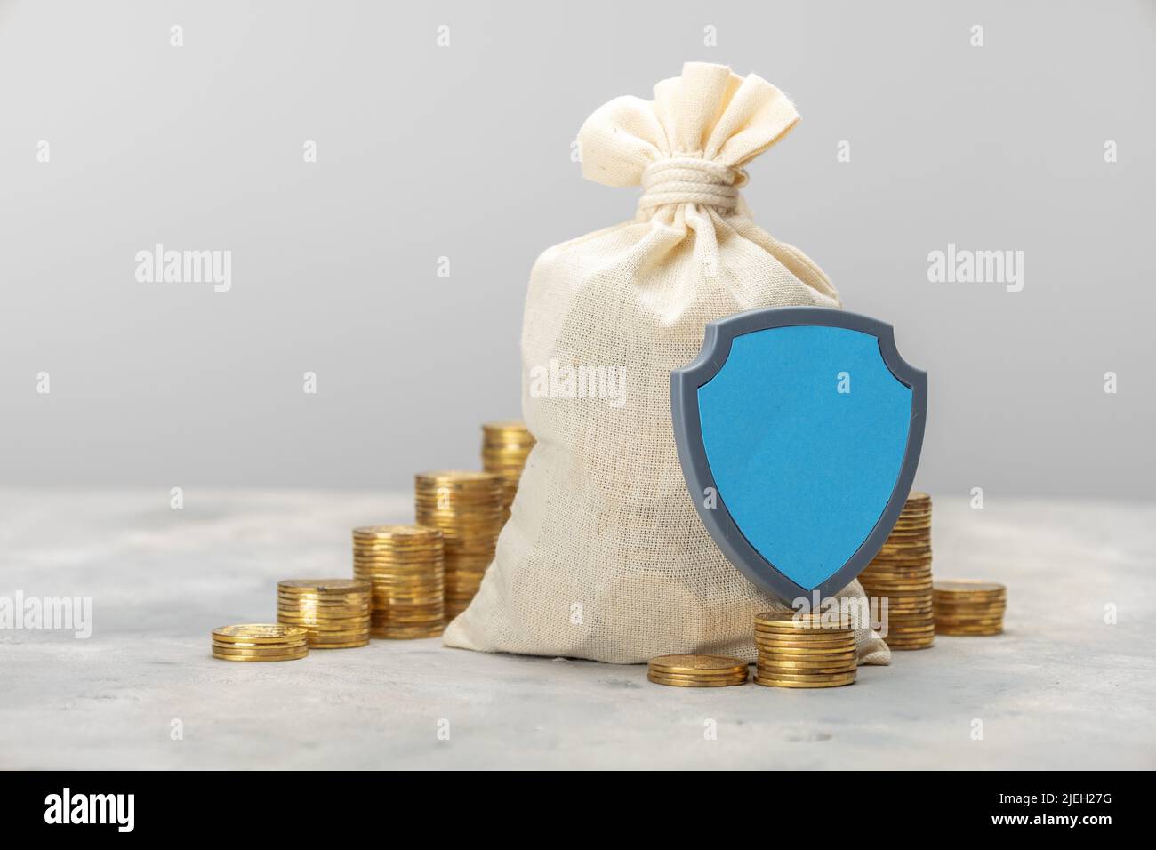 Money bag and a stack of gold coins with a shield. Savings insurance concept. Stock Photo