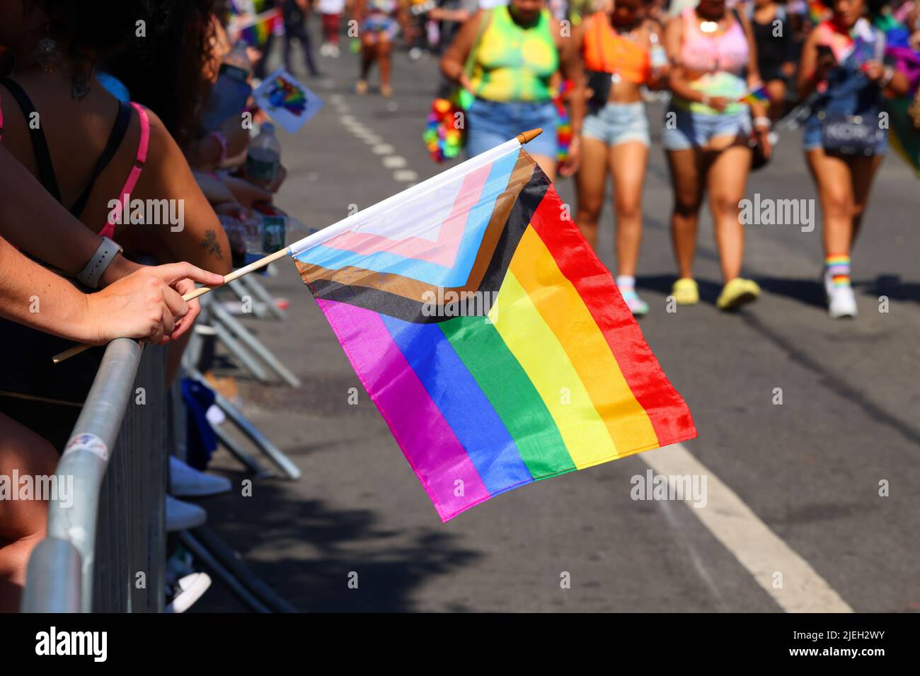 New York, June 26, 2022. A person holds a Progress Pride Flag at NYC Pride. The flag includes black and brown stripes representing marginalized LGBTQ+ Stock Photo