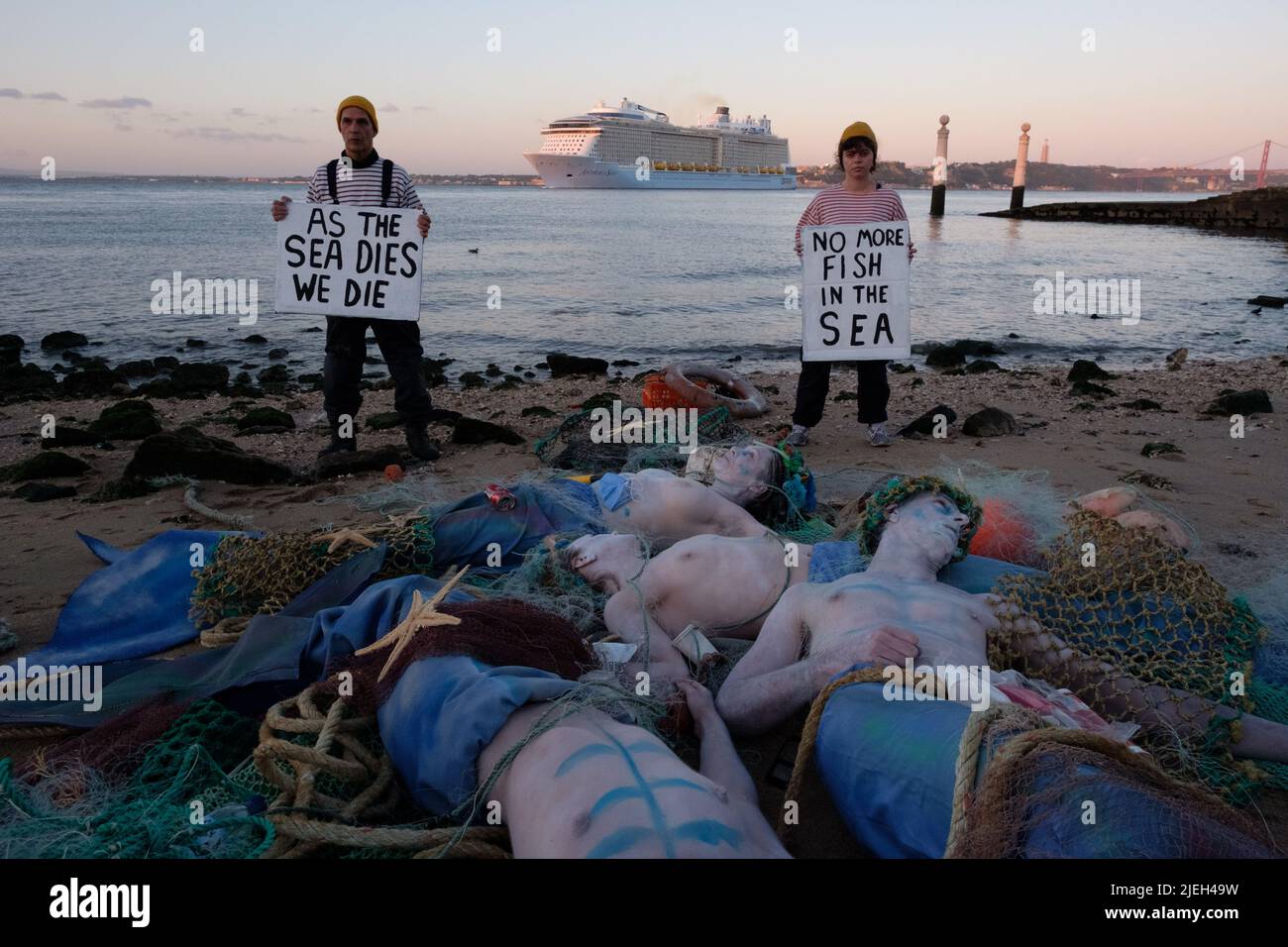 Lisbon, Portugal. 27th JUN 2022. Members of Ocean Rebellion perform a creative theatrical action where Dead Merfolk are washed-up at dawn, caught in a trawler-net along with debris from the sea (both plastics and seakill). Ocean Rebellion demands the UN calls for an end to all national fuel subsidies to fishing fleets and bans bottom trawling on the grounds of both needless biodiversity loss, through bycatch, and blue carbon release. Credit: Dan Pearson/Alamy Live News Stock Photo