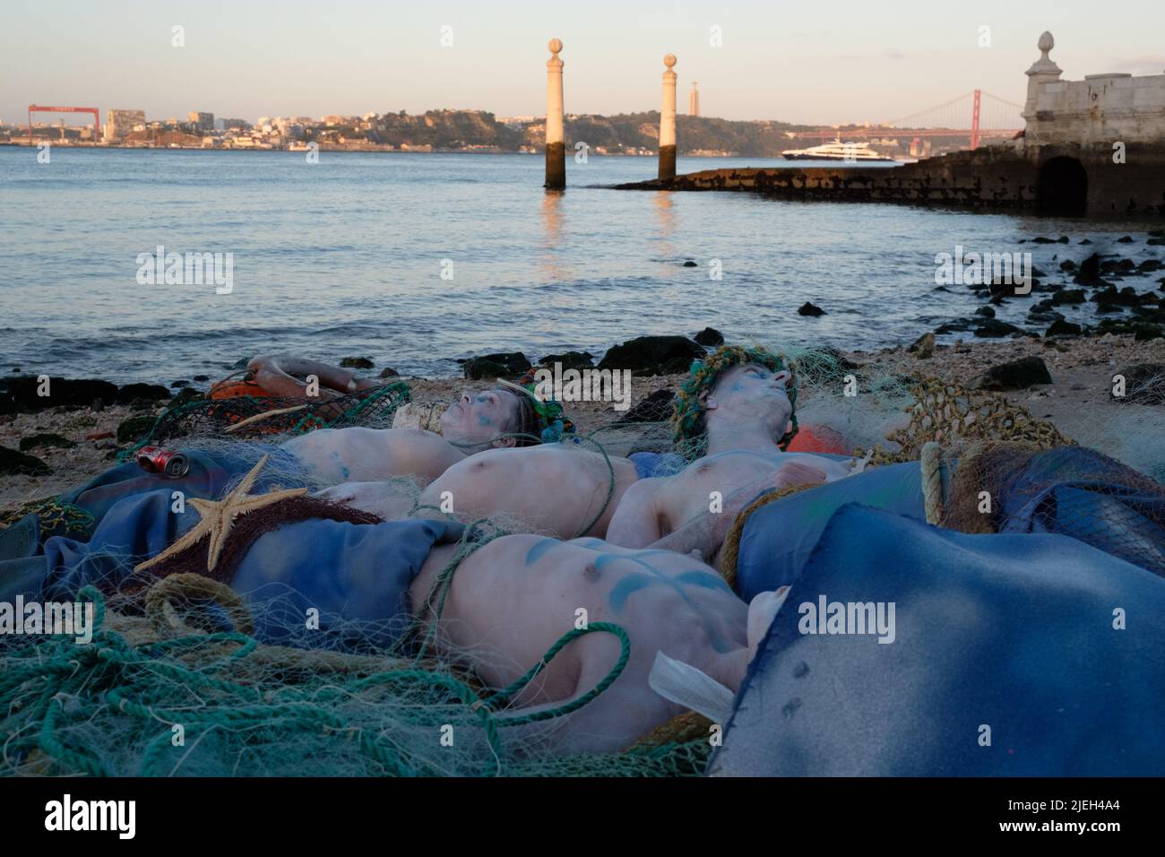 Lisbon, Portugal. 27th JUN 2022. Members of Ocean Rebellion perform a creative theatrical action where Dead Merfolk are washed-up at dawn, caught in a trawler-net along with debris from the sea (both plastics and seakill). Ocean Rebellion demands the UN calls for an end to all national fuel subsidies to fishing fleets and bans bottom trawling on the grounds of both needless biodiversity loss, through bycatch, and blue carbon release. Credit: Dan Pearson/Alamy Live News Stock Photo