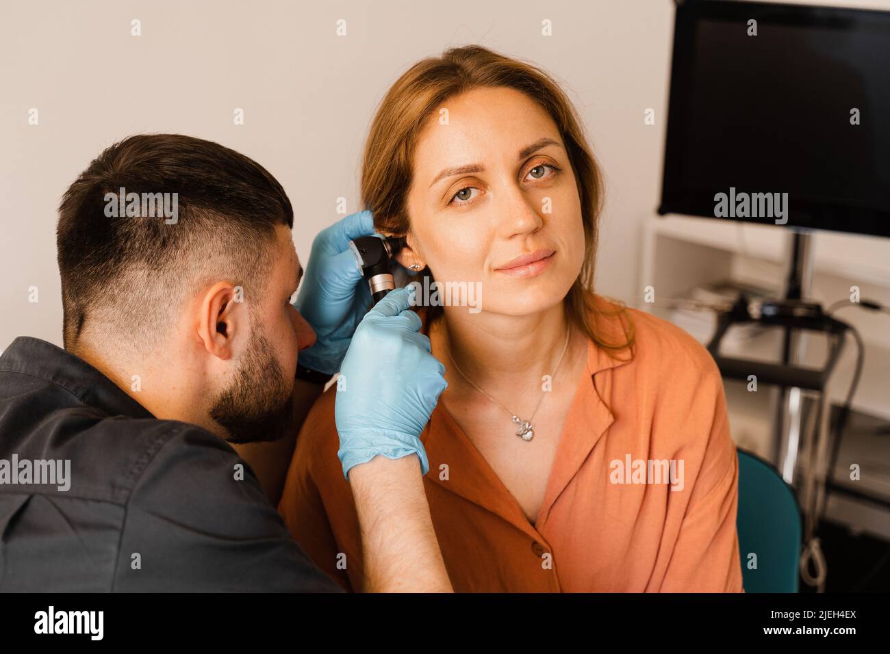 ENT doctor with otoscope. Otoscopy. Otolaryngologist looks through otoscope the ears of woman. Treatment ear pain Stock Photo