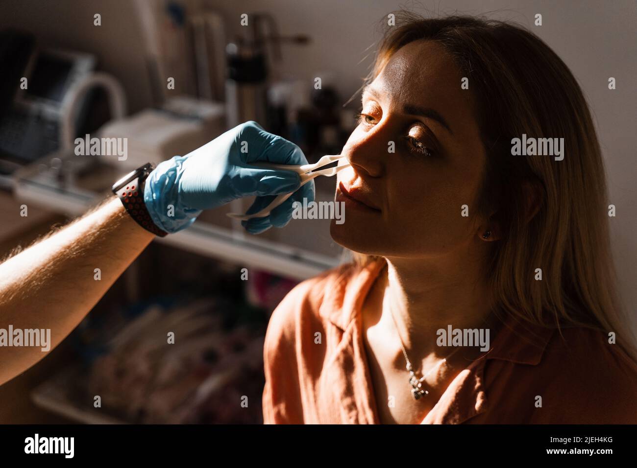 Rhinoscopy of woman nose. Consultation with doctor. Otolaryngologist examines girl nose before procedure of endoscopy of nose Stock Photo