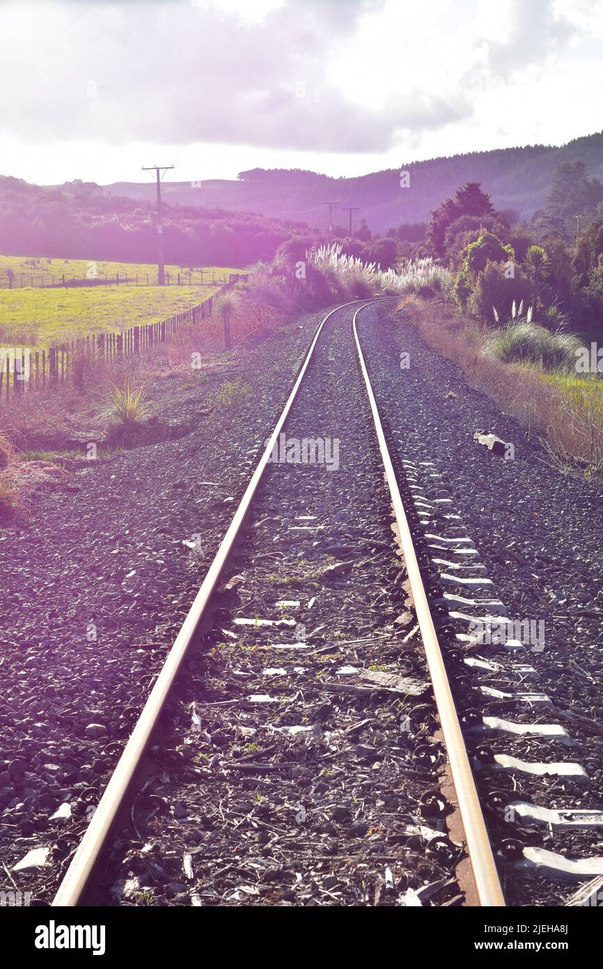 Unused railway tracks running along fenced paddock in New Zealand countryside. Location: Rodney District New Zealand Stock Photo