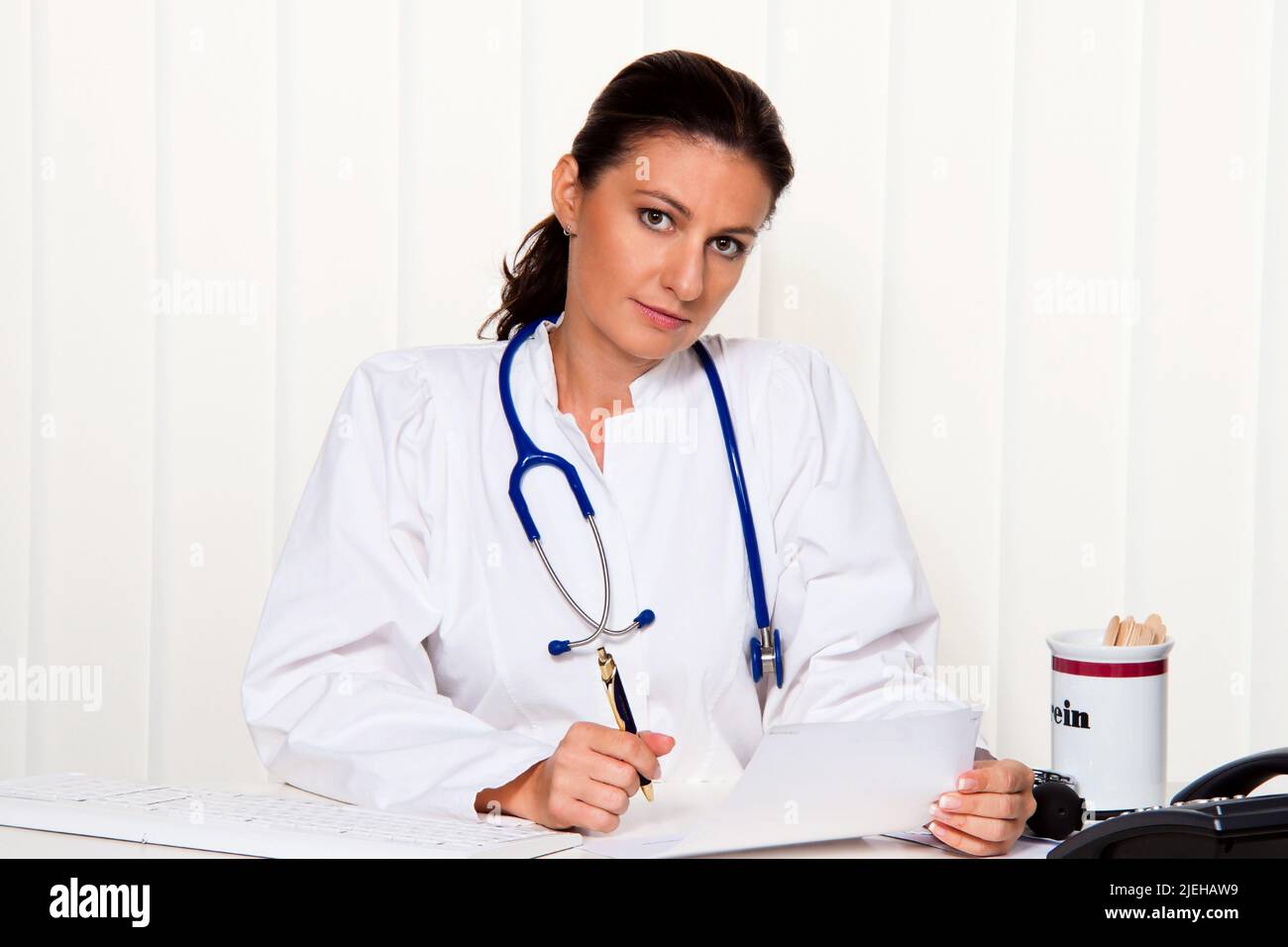 Junge ƒrztin in ihrer Arztpraxis am Schreibtisch Stock Photo