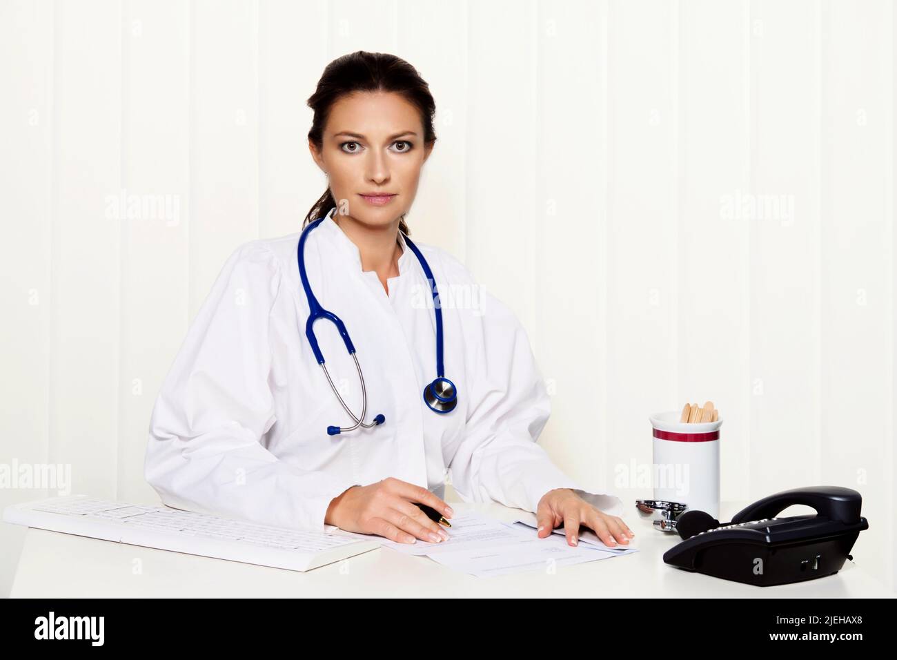 Junge Ärztin in ihrer Arztpraxis am Schreibtisch Stock Photo