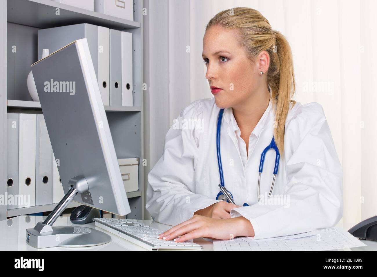 Eine junge Ärztin mit Stethoskop in ihrer Arztpraxis. Stock Photo