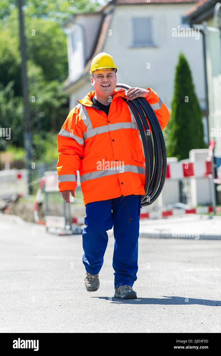 Bauarbeiter mit einem Wasserschlauch in der Hand, Mann, 35, 40, Jahre, gelber Schutzhelm, Stock Photo