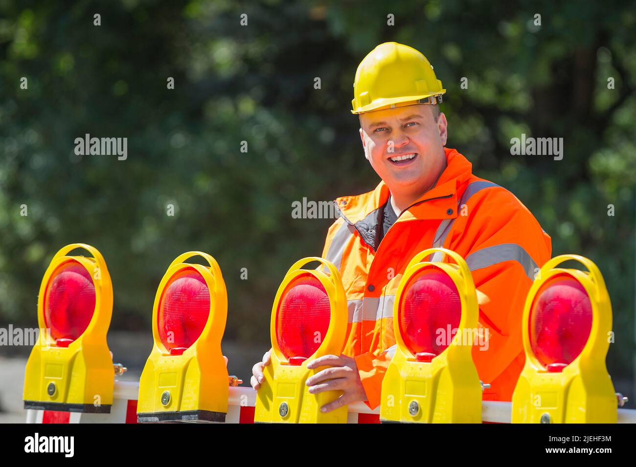 Ein Arbeiter überprüft die Baustellenabsperrung , Mann, 35, 40, Jahre, gelber schutzhelm, Schutzkleidung, Warnweste, Stock Photo