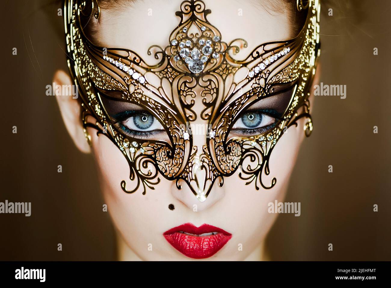 Junge, blonde Frau mit goldener, venezianischer Maske - woman with Venetian mask Stock Photo