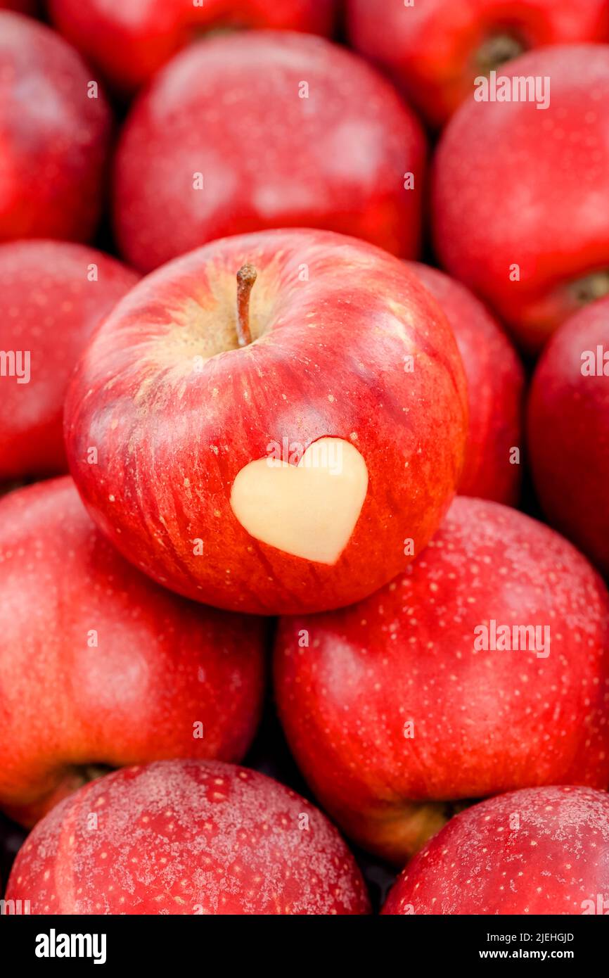 Ein roter Apfel mit Herz liegt auf anderen roten Äpfeln, Obst, Frucht, Früchte, Liebesapfel, Stock Photo