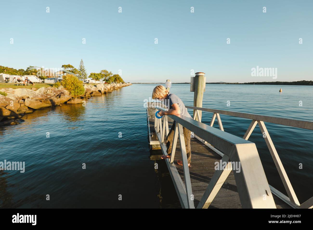 Boy fishing with hand reel on jetty at Iluka, NSW Australia Stock Photo