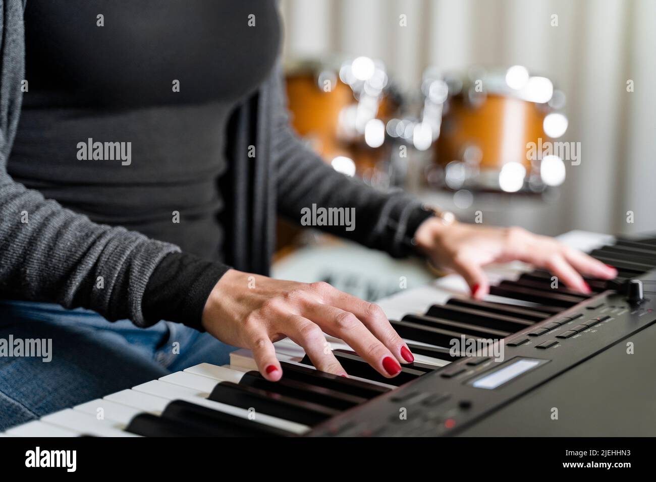 Young woman playing digital keyboard or electronic piano on concert