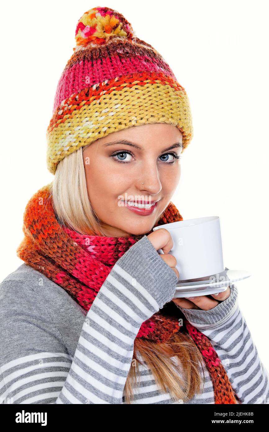 Eine junge blonde Frau mit Schal und Mütze trinkt einen Kaffee im Winter, Aufwärmen, Getränk, Pudelmütze, Kaffeebecher, Stock Photo