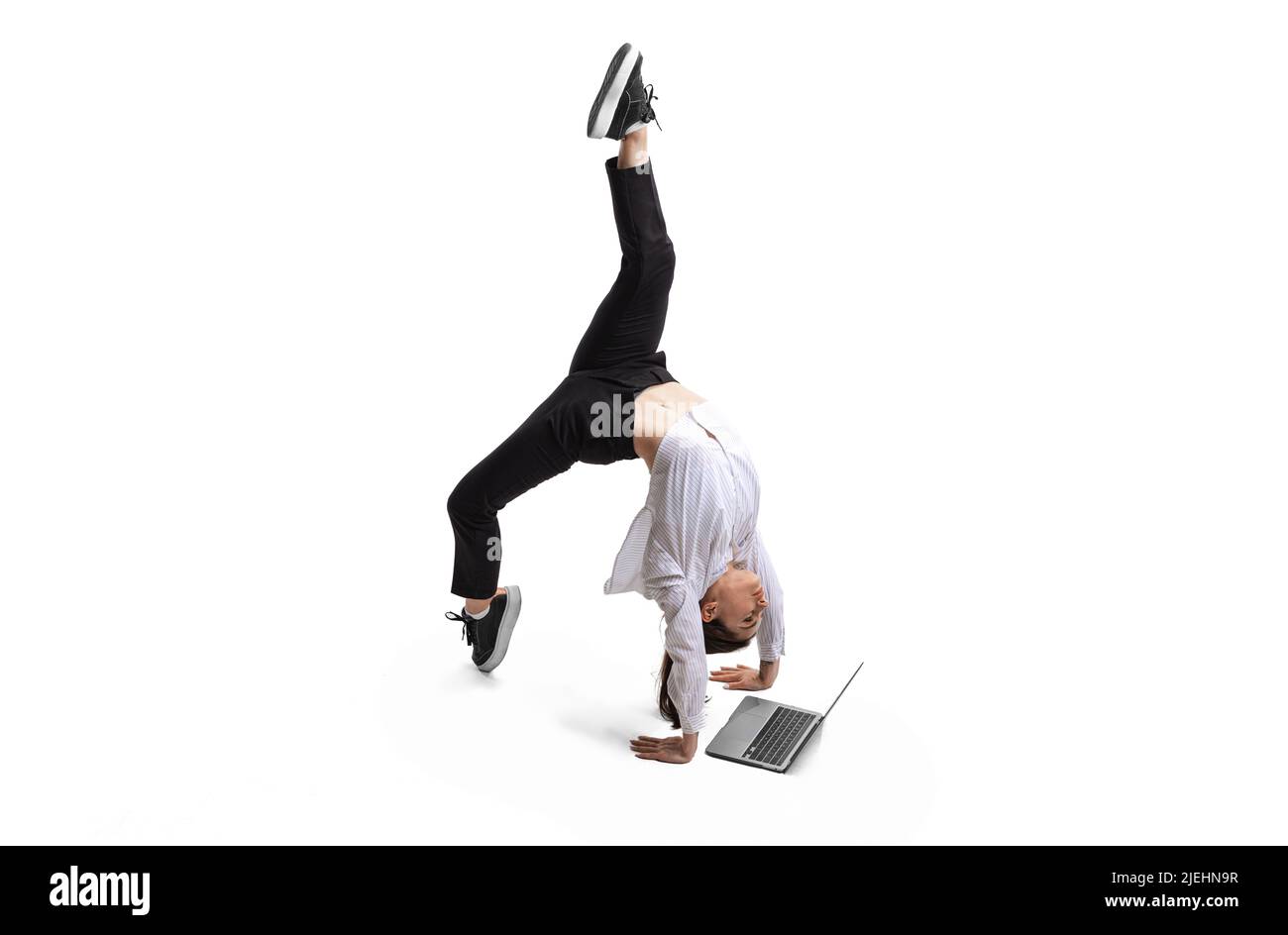 Flexible young girl working with laptop isolated over white studio ...