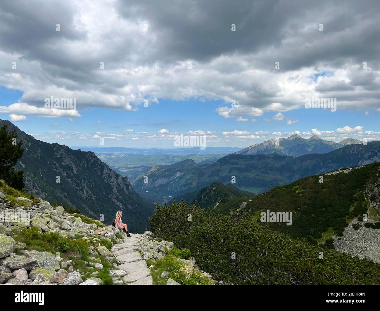 Panoramic scenic view of moutains in Zakopane, Poland with one blond woman relaxing on a hill in the background. Active life concept. Hiking in the mo Stock Photo