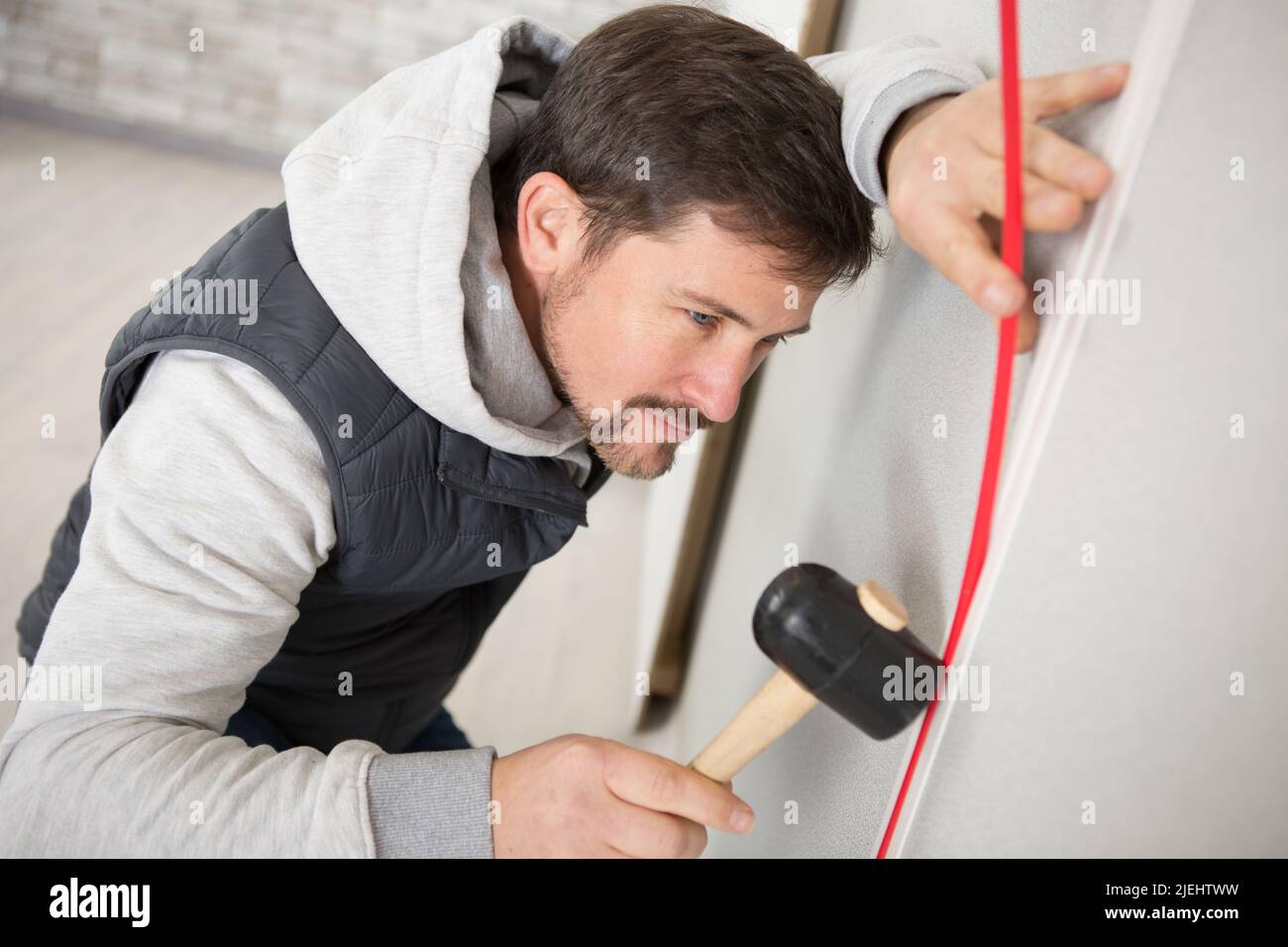 young builder using a hammer to remove walls plaster Stock Photo Alamy