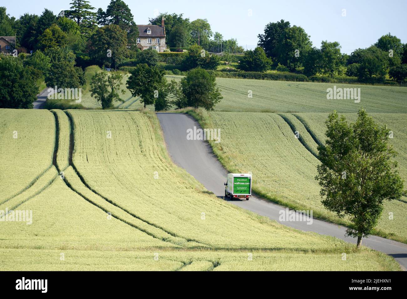 A Waitrose home delivery van makes it's way through the countryside to a make an online supermarket delivery at a customers home Stock Photo