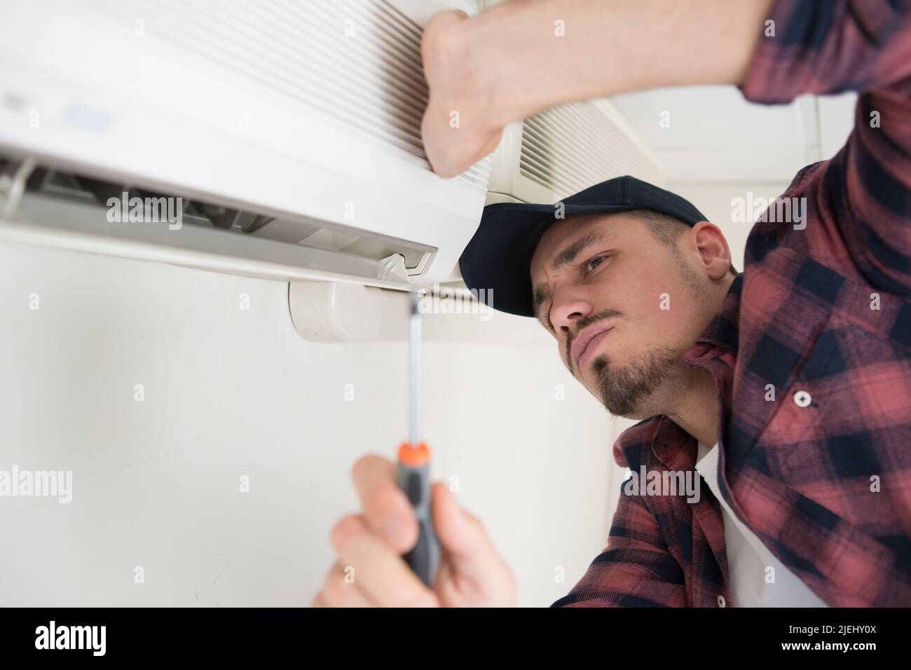 male technician installing outdoor air conditioning unit Stock Photo