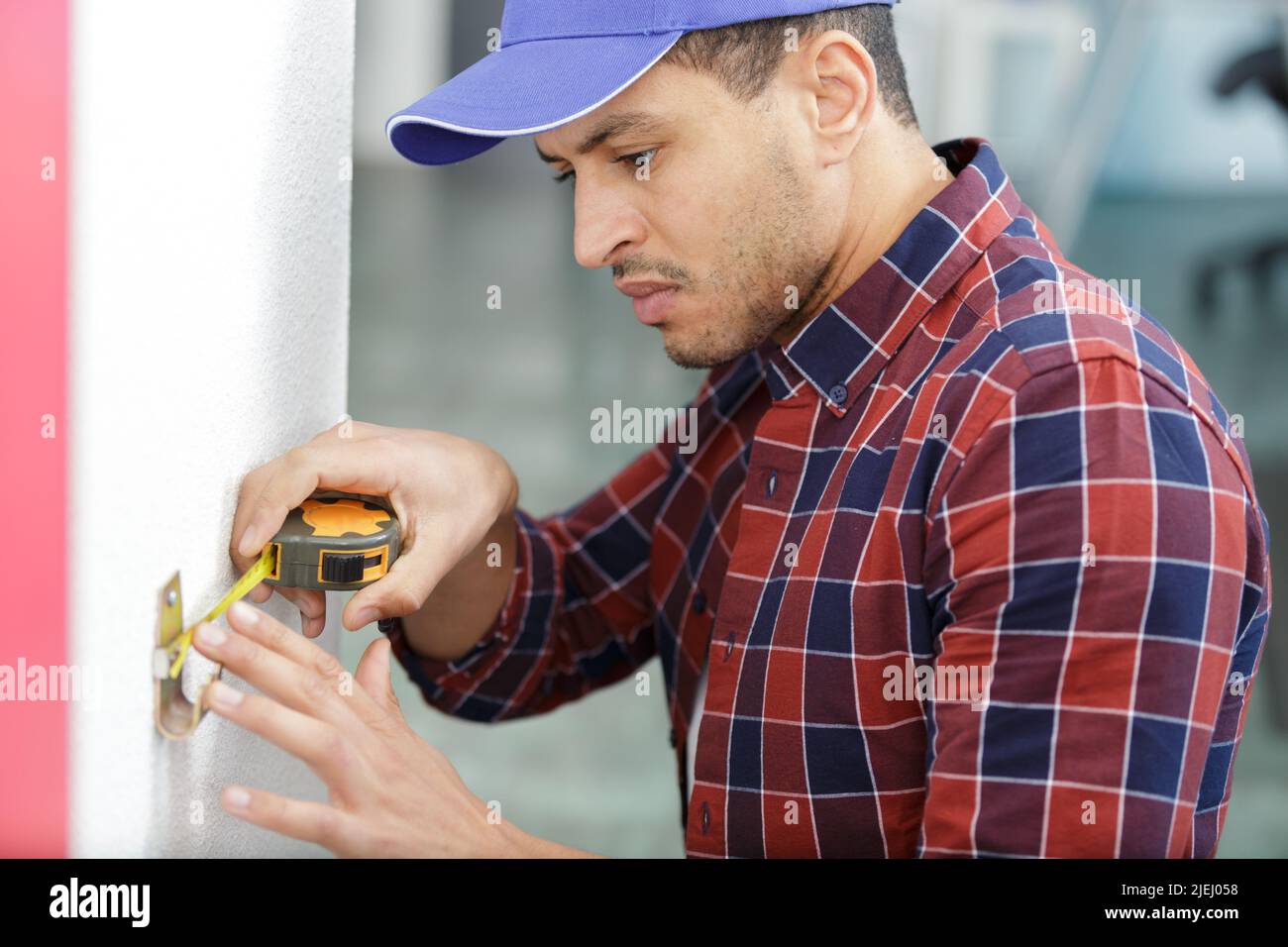 handyman installing hook on the wall measuring with ruler Stock Photo