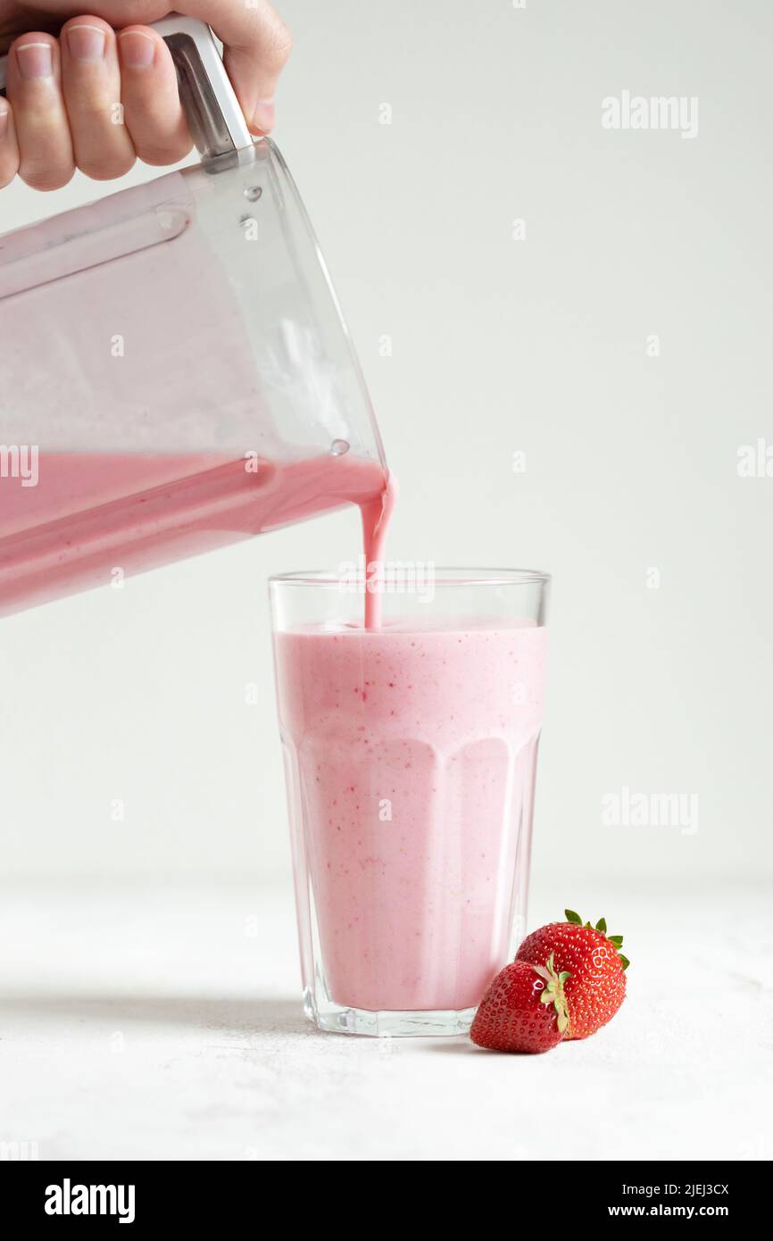 Strawberry smoothie pouring in the glass from blender. Stock Photo