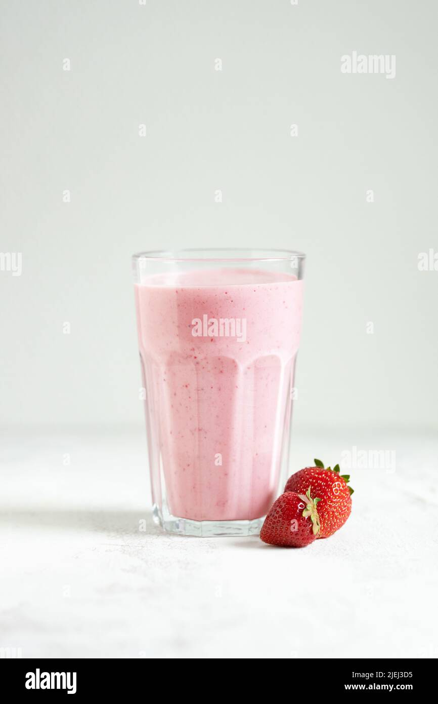 Strawberry smoothie in the glass on white table. Stock Photo