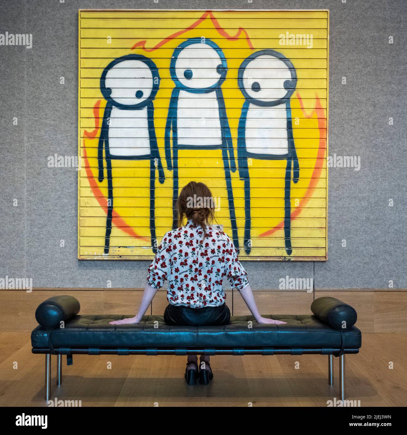 London, UK.  27 June 2022. A staff member views “Children of Fire”, 2011, by STIK (Est. £120,000 - £180,000) at a preview of Post-War and Contemporary Art sale.  The auction will take place on 30 June at Bonhams New Bond Street galleries.  Credit: Stephen Chung / Alamy Live News Stock Photo