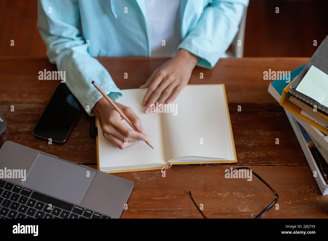 Top view shot of woman writing making list taking notes in notepad working or learning on laptop indoors- educational course or training, seminar Stock Photo
